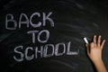 Kid hand write message back to school with white chalk on black chalkboard Royalty Free Stock Photo