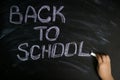 Kid hand write message back to school with white chalk on black chalkboard Royalty Free Stock Photo