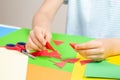 Kid hands cutting red color paper