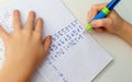 Kid hands doing math homework. Close up of young boy hand holding pen and writing a math homework close-up. concept of education Royalty Free Stock Photo