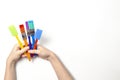 Kid hands holding colorful paintbrushes over white background