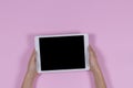 Kid hands holding digital tablet computer on pastel pink background. Top view Royalty Free Stock Photo