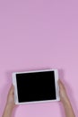 Kid hands holding digital tablet computer on pastel pink background. Top view Royalty Free Stock Photo
