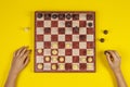 Kid hands over a chessboard playing chess game on yellow background, top view Royalty Free Stock Photo