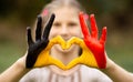 Kid hands painted in Belgium flag color show symbol of heart and love gesture