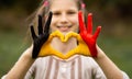 Kid hands painted in Belgium flag color show symbol of heart and love gesture