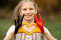 Kid hands painted in Belgium flag color show symbol of heart and love gesture