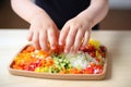 kid hands placing vegetables on sushi rice