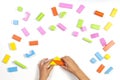 Kid hands playing with colorful wooden building blocks on white table background. Top view Royalty Free Stock Photo