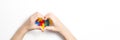 Kid hands in the shape of heart and colorful heart made of plastic construction puzzle pieces on white background. World Royalty Free Stock Photo
