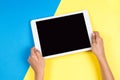 Kid hands with tablet computer on blue and yellow background Royalty Free Stock Photo