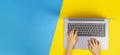 Kid hands typing on laptop computer keyboard, top view, yellow and blue background Royalty Free Stock Photo