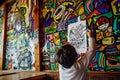 kid hanging a drawing on a cafe wall covered in vivid artwork