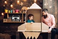 Kid happy sit in cardboard hand made rocket. Boy play with dad, father, little cosmonaut sit in rocket made out of Royalty Free Stock Photo