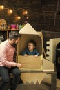 Kid happy sit in cardboard hand made rocket. Child boy play cosmonaut, astronaut. Parenthood concept. Boy play with dad