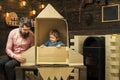 Kid happy sit in cardboard hand made rocket. Parenthood concept. Child boy play cosmonaut, astronaut. Boy play with dad