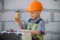 Kid in hard hat holding hammer. Little child helping with toy tools on construciton site. Kids with construction tools Royalty Free Stock Photo