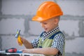 Kid in hard hat holding hammer. Little child helping with toy tools on construciton site. Kids with construction tools Royalty Free Stock Photo