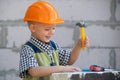 Kid in hard hat holding hammer. Little child helping with toy tools on construciton site. Kids with construction tools Royalty Free Stock Photo