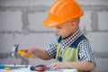 Kid in hard hat holding hammer. Little child helping with toy tools on construciton site. Kids with construction tools Royalty Free Stock Photo