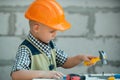 Kid in hard hat holding hammer. Little child helping with toy tools on construciton site. Kids with construction tools Royalty Free Stock Photo