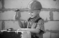 Kid in hard hat holding hammer. Little child helping with toy tools on construciton site. Kids with construction tools Royalty Free Stock Photo