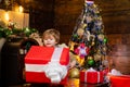 Kid having fun near Christmas tree indoors. Happy child holding a giant red gift box with both hands. Christmas Royalty Free Stock Photo