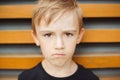 Kid having grumpy dissatisfied facial expression. Child being grounded by parents for bad behavior. Sad emotional boy