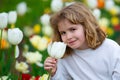 Beautiful kid smelling the white tulip flower on tulip fields. Child in smelling tulip in spring park. Close up kids Royalty Free Stock Photo