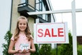 Kid holding carton house model near board with sale letters Royalty Free Stock Photo