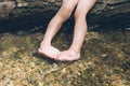 Kid holding feet in the river while sitting on log Royalty Free Stock Photo