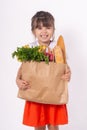 Kid holding paper grocery bag full of vegetables milk, bread. Happy child with grocery bag full of healthy food isolated on white.