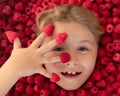 Kid holding raspberries on her fingers. Happy little child face with raspberry. Child picking raspberry. Kids pick fresh Royalty Free Stock Photo