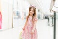 Kid holding shopping bags. Little girl in pink dress looking through shop window. A smiling laughing girl in a pink dress with Royalty Free Stock Photo