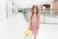 Kid holding shopping bags. Little girl in pink dress looking through shop window. A smiling laughing girl in a pink dress with Royalty Free Stock Photo