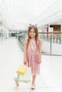 Kid holding shopping bags. Little girl in pink dress looking through shop window. A smiling laughing girl in a pink dress with Royalty Free Stock Photo