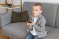 Kid holding TV remote controller. Boy without parental control watching television