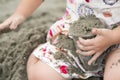 Kid holds and plays sand in the plastic cup on the beach