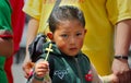 Kid holds a straw rood in a religious ceremony