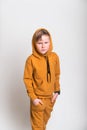 Kid in hood from yellow fashion sport suit hoodie. Blond kid face in a hood looks from under a forehead. Stylish child Royalty Free Stock Photo