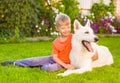 Kid hugging White Swiss Shepherd dog together on green grass Royalty Free Stock Photo