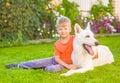 Kid hugging White Swiss Shepherd dog together on green grass Royalty Free Stock Photo