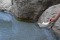 Kid launching small white paper boat on water outdoors, closeup. Space for text