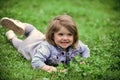 Kid lays on grass. Child smile on green grass