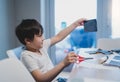 Kid learning how to use the scissors cut the paper,Schoolboy using scissors cutting black paper in square shape,Child showing art Royalty Free Stock Photo