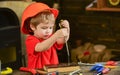 Kid learning to use screwdriver. Concentrated kid in orange helmet working in workshop. Future occupation concept Royalty Free Stock Photo