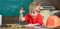 Kid learning to use screwdriver. Concentrated kid working in repairs workshop. Future occupation concept