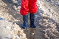 Kid legs in rainboots standing in the ice puddle