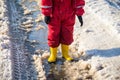 Kid legs in rainboots standing in the ice puddle