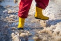 Kid legs in rainboots running in the ice puddle